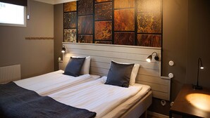 Een tweepersoonsbed met twee kussens, een nachtkastje en een muur met een houten paneeldecor.