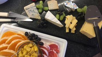 Tabla de formatge amb diferents tipus de formatge i raïm, un ganivet i una taula de tallar.