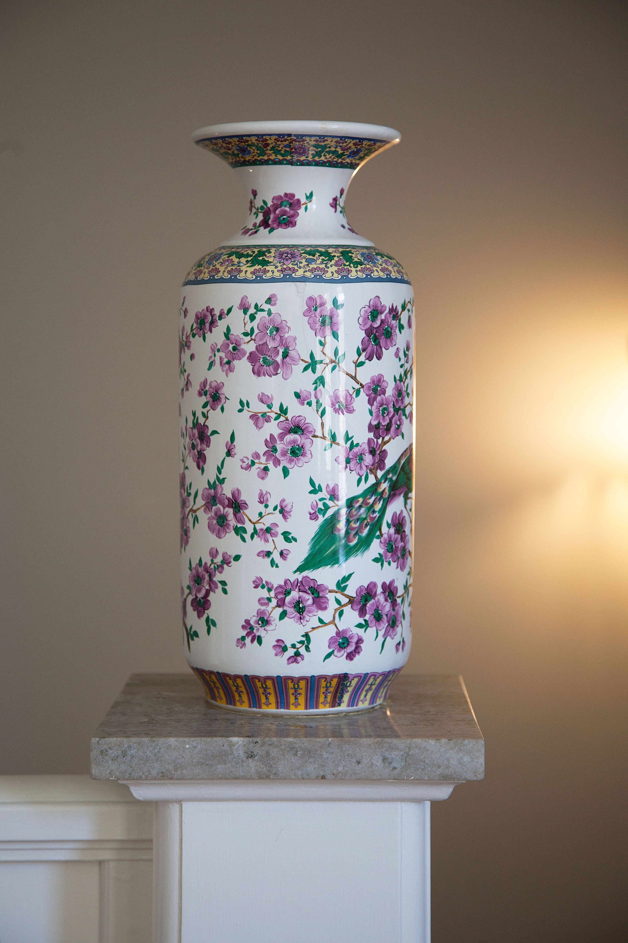 Un grand vase orné de motifs floraux, posé sur un piédestal.