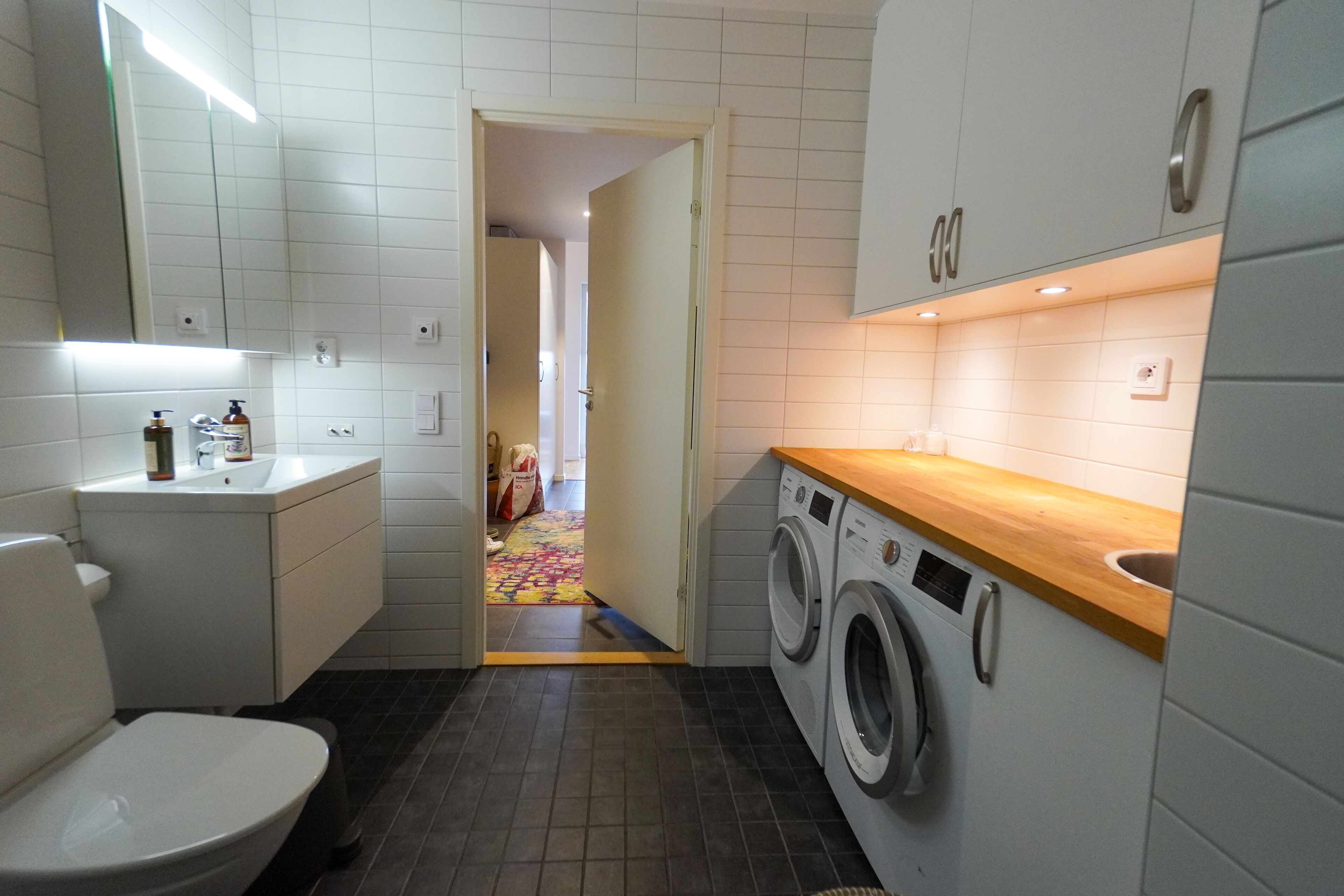 Et lille badeværelse med toilet, vask og vaskemaskine.