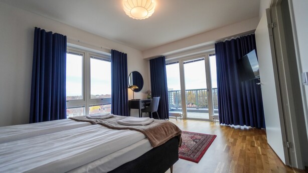 Een moderne hotelkamer met een groot bed, een bureau, een stoel, een televisie en een balkon met uitzicht.