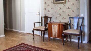 A dining area with a wooden table and chairs, a patterned rug, and a door with a number 37 on it.