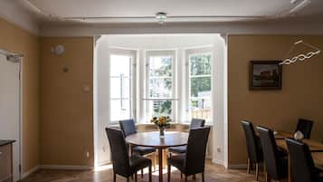 Un comedor con una mesa redonda de madera, sillas negras y un jarrón de flores.