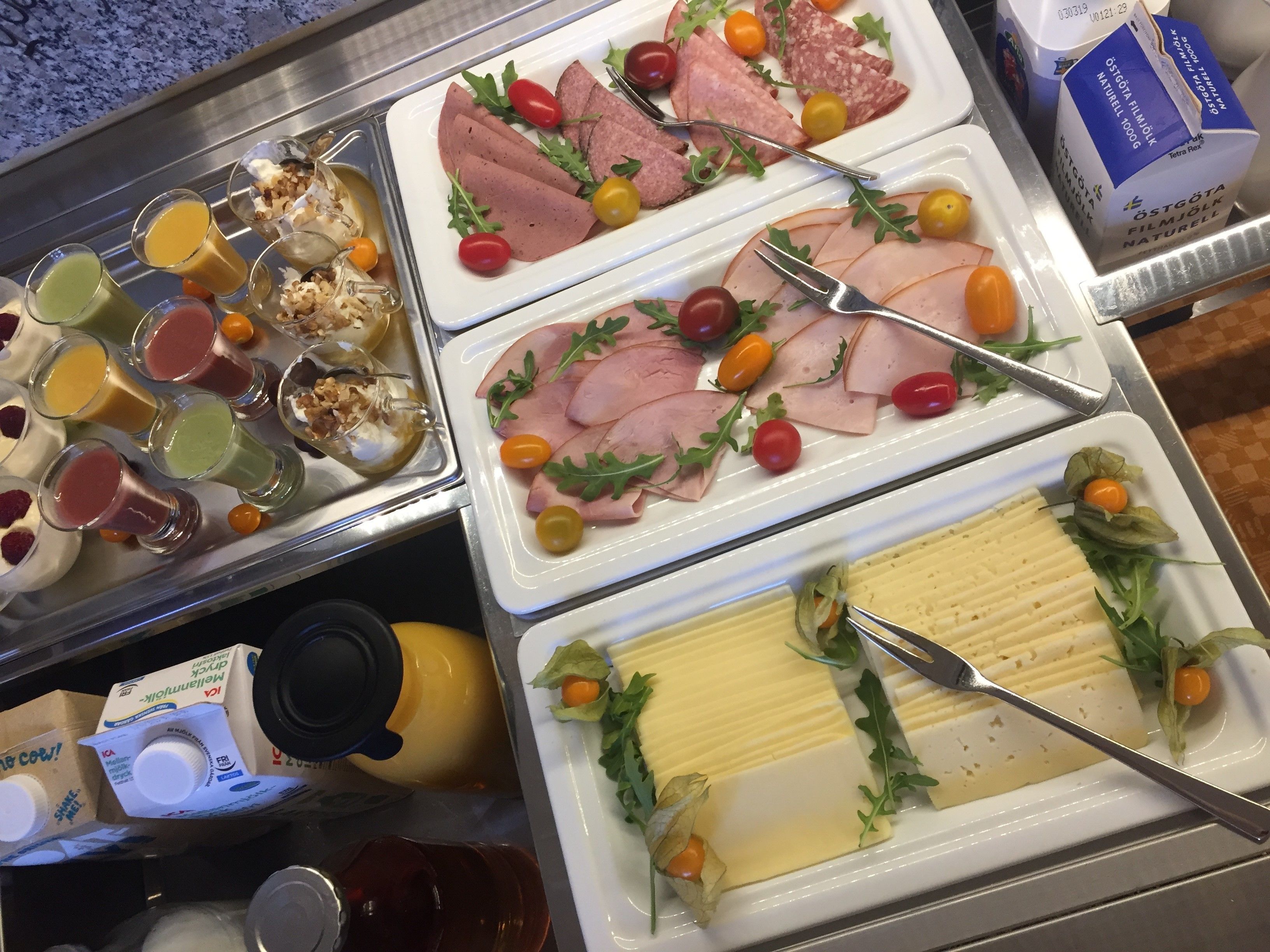 Un bufé con diversos alimentos, incluyendo carnes cortadas, quesos y verduras frescas.
