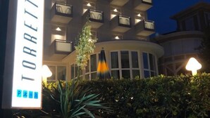 Ein modernes Hotelgebäude namens TORRETTA mit beleuchteter Beschilderung und mehreren Balkonen.