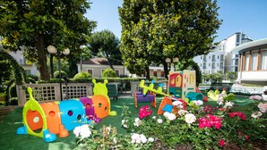 Ein Spielplatz mit bunten Spielgeräten und ein Blumengarten.