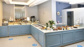 Ein Frühstücksbuffet mit einer Auswahl an Gebäck und Backwaren, einer Kaffeemaschine und einem Blumentopf.
