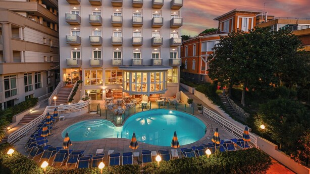 Ein Hotel mit Poolbereich, mehreren Balkonen und einem gut beleuchteten Eingang.