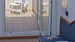 Ein Zimmer mit einem Bett, einem Deckenventilator und Meerblick durch eine geöffnete Schiebetür.