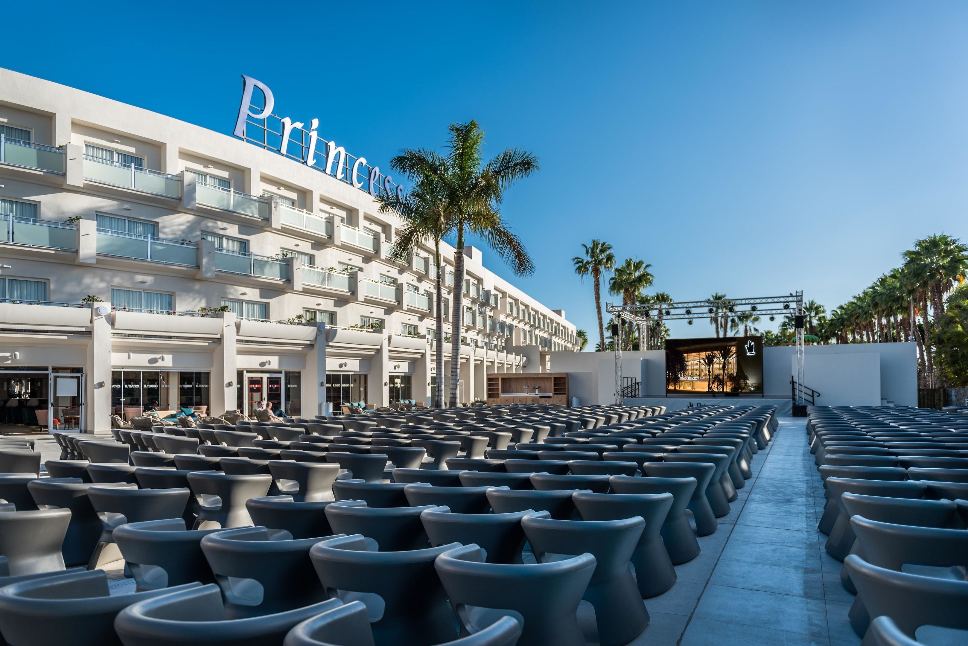 A hotel with a prominent 'Princess' sign, outdoor seating area, and palm trees.
