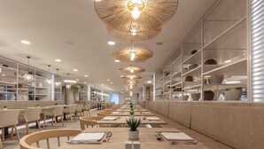 A modern restaurant with long tables, wooden chairs, and hanging pendant lights. - Hotel Maspalomas Princess-All Inclusive (San Bartolomé de Tirajana)