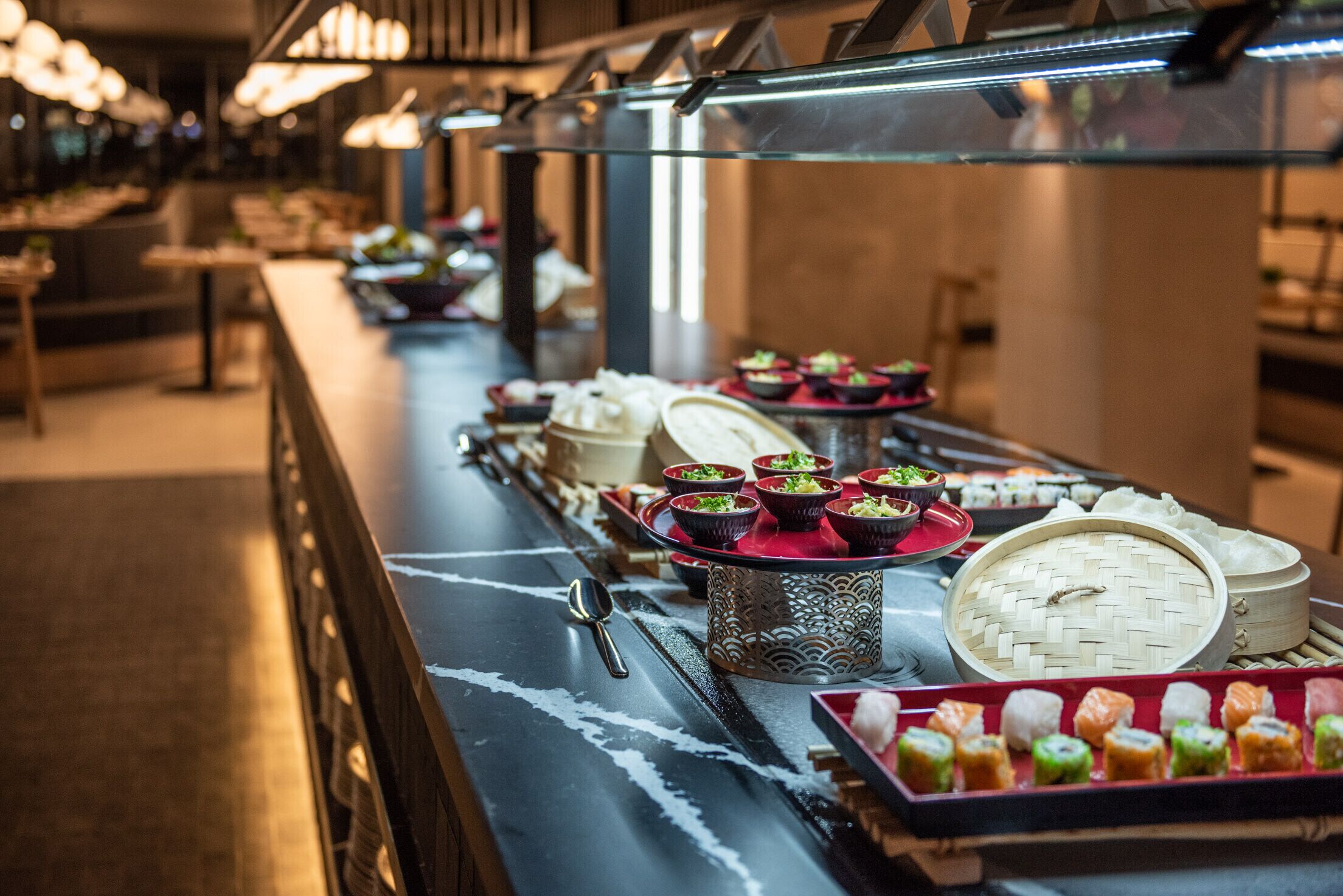 A buffet with various dishes and a spoon on a table.