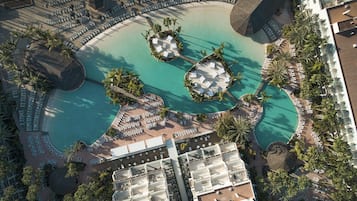 Vue aérienne d’un complexe hôtelier doté d’une grande piscine centrale, de nombreux espaces de détente et de différents types d’hébergements.