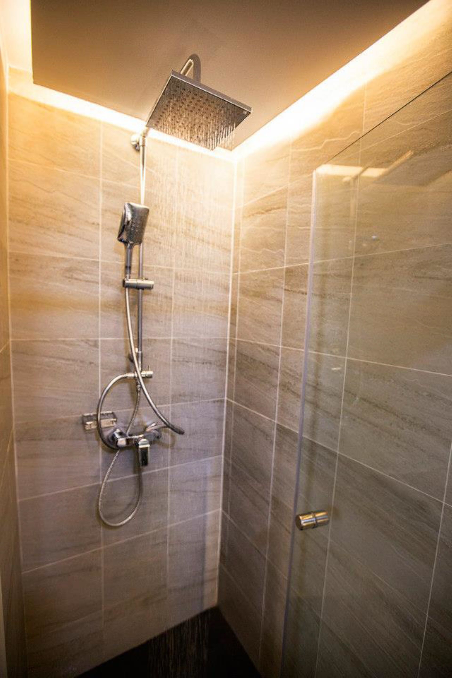 Una ducha moderna con cabezal de ducha manual y otro tipo lluvia instalado en la pared.