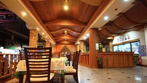 A restaurant with wooden ceiling, tables with floral tablecloths, and a counter with a menu. - P72 Hotel (Pattaya)
