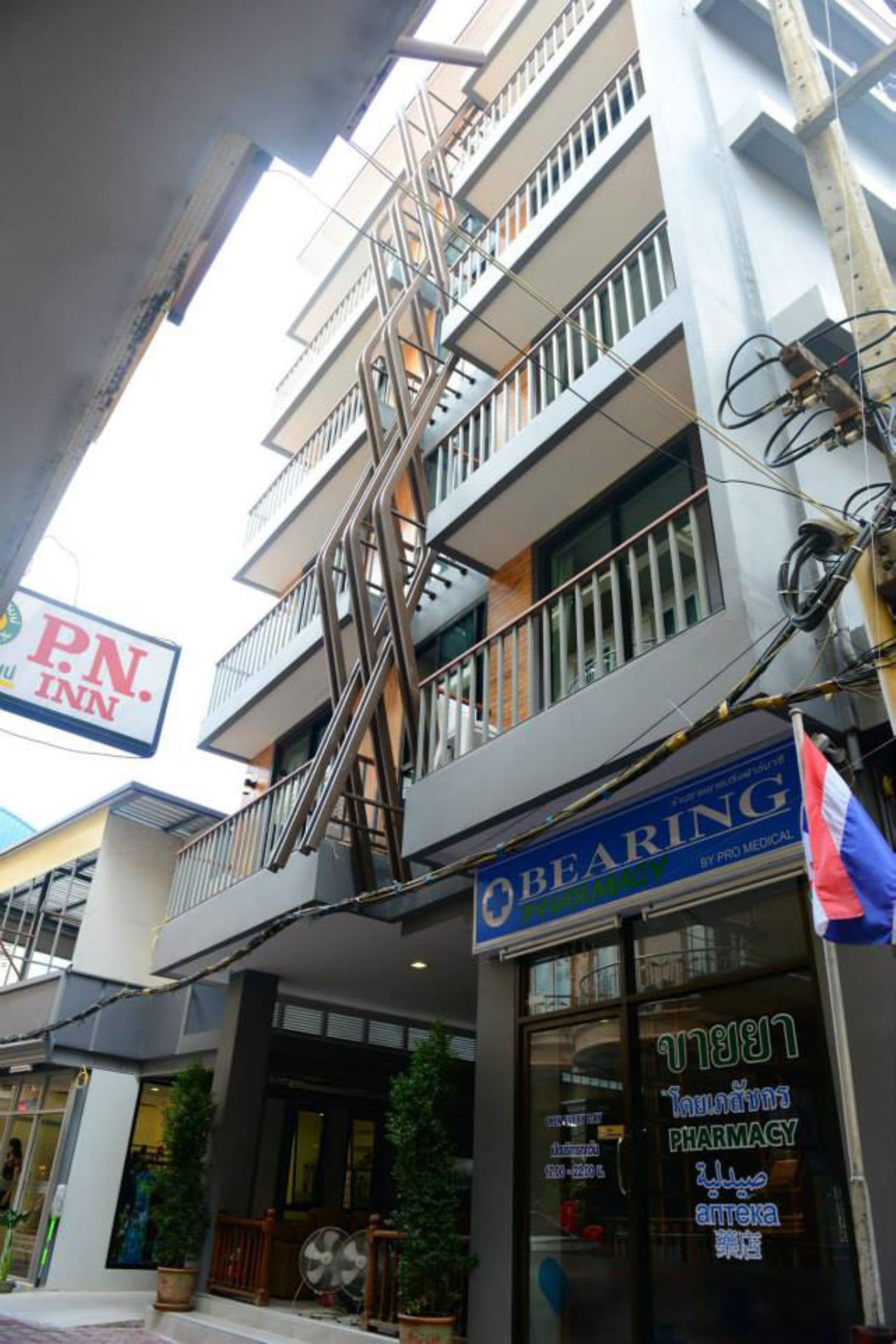 Un edificio de varios pisos con una farmacia en la planta baja, un letrero que dice P.N. Inn en la parte superior y barandilla de balcón.