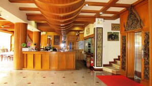 A reception area with a wooden reception desk, a staircase, and a red carpet leading to an elevator. - P72 Hotel (Pattaya)