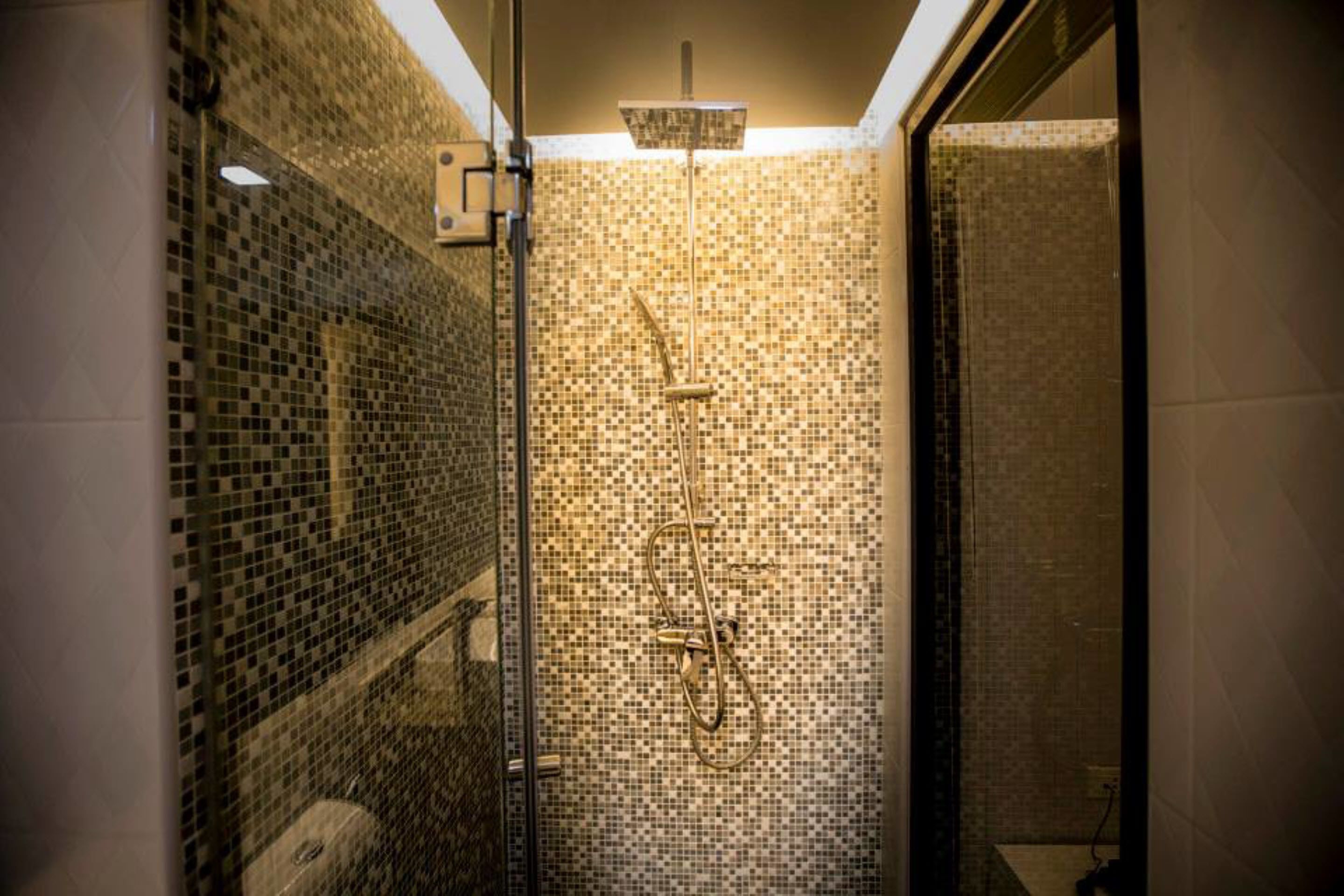 A shower with mosaic tile walls and a glass enclosure.