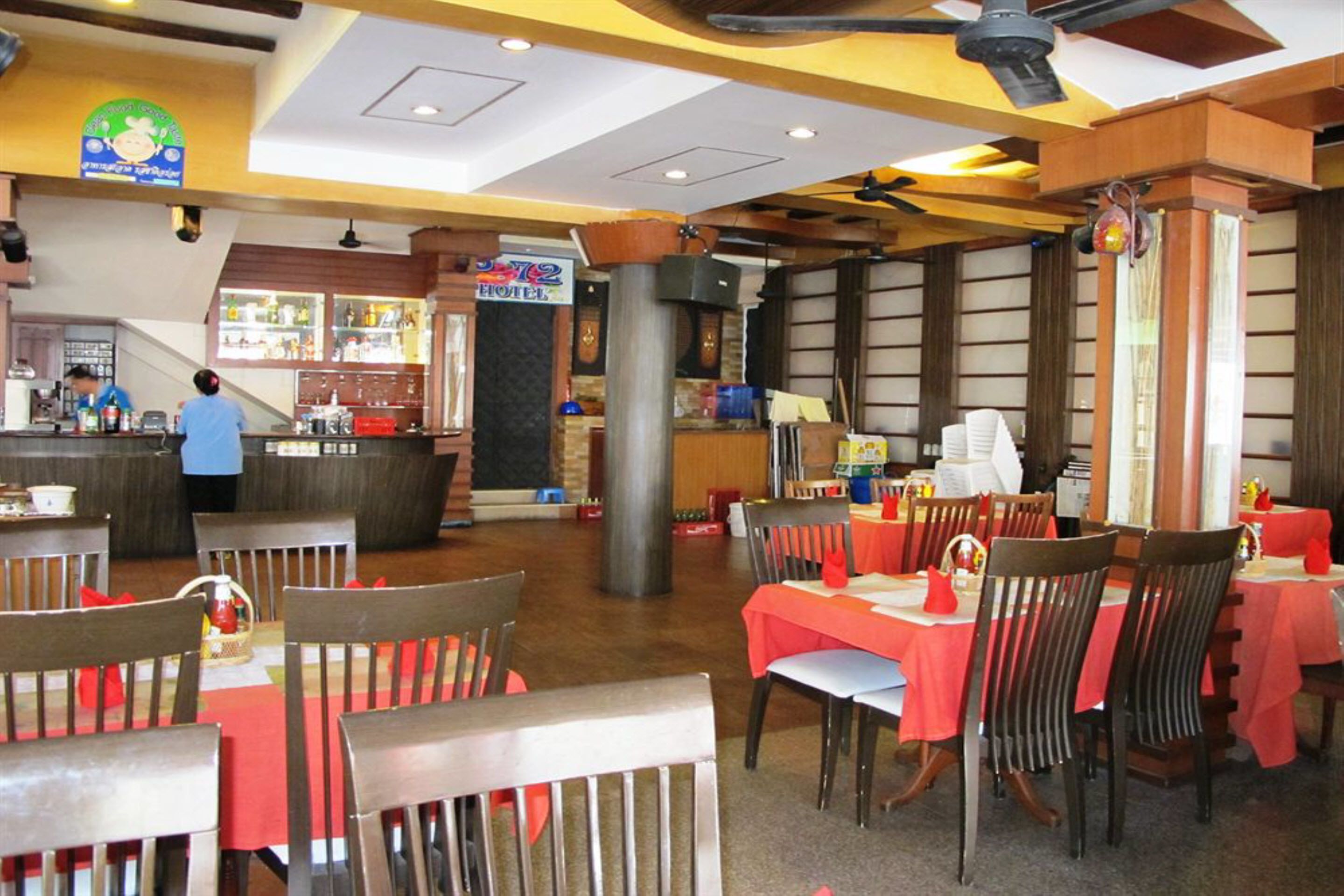 A restaurant with wooden chairs and tables, a bar area, and a visible counter.
