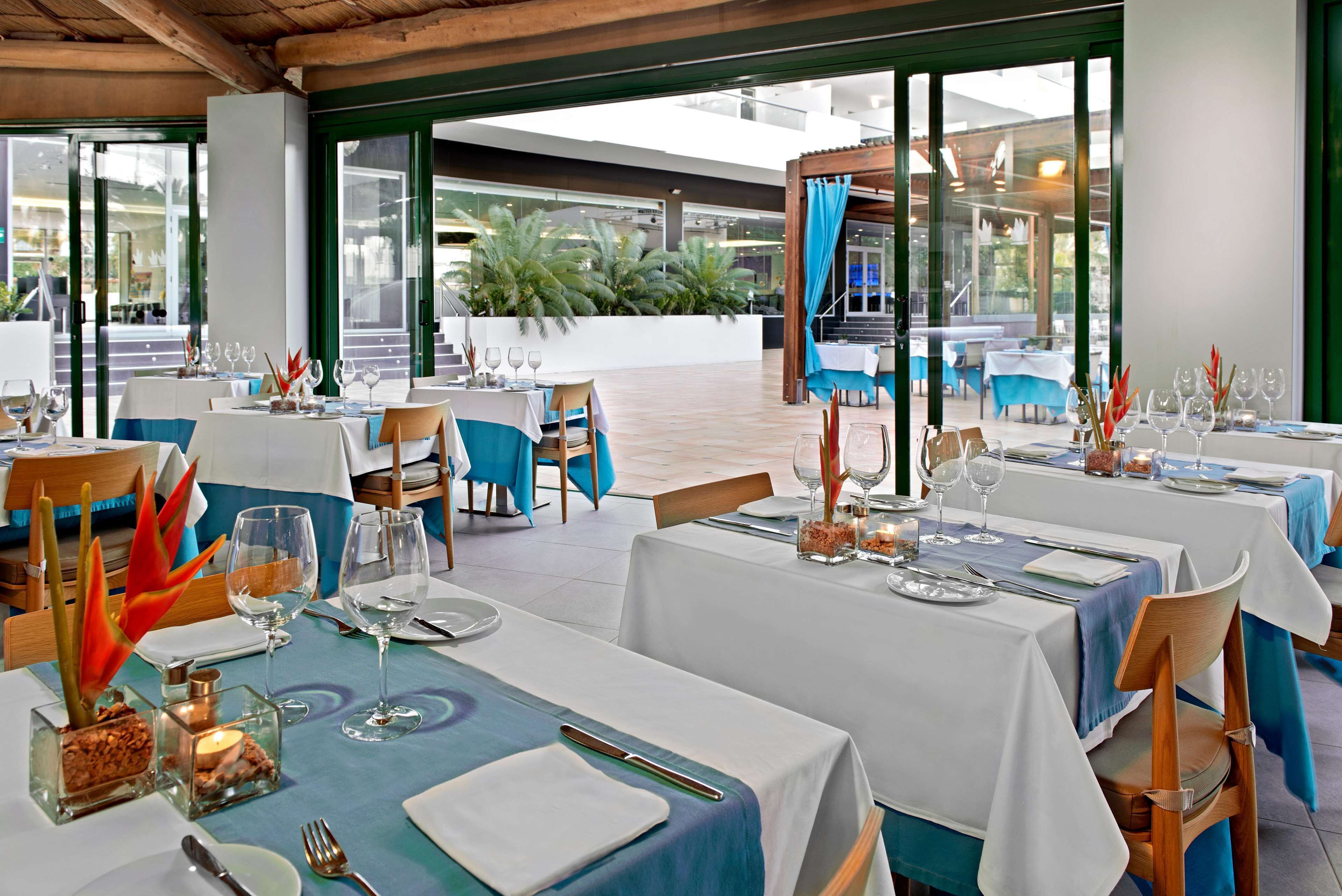 A restaurant with tables set for dining, featuring a view of the outdoor area.