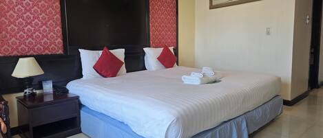 A hotel room with a large bed, a nightstand with a lamp, and a framed picture on the wall.