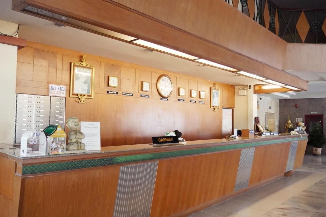 A hotel reception desk with a safety box, framed certificates, and a clock.