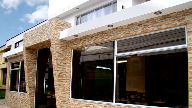 A modern building with large windows and a stone facade. - Hotel Boutique Feria Internacional (Bogotá)