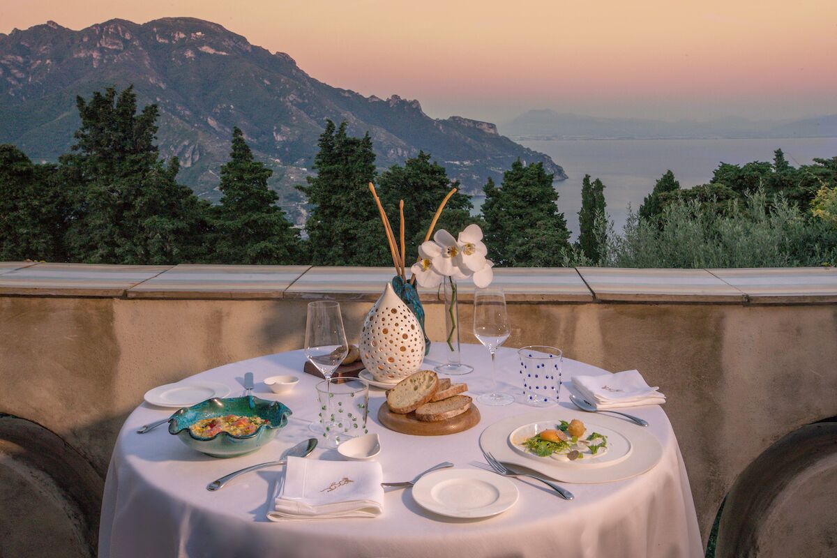 A table set for a meal with a view of mountains and a body of water.