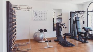 Un gimnasio con equipo de ejercicio, una barra de dominadas, una bicicleta estática y una pelota de ejercicios grande.