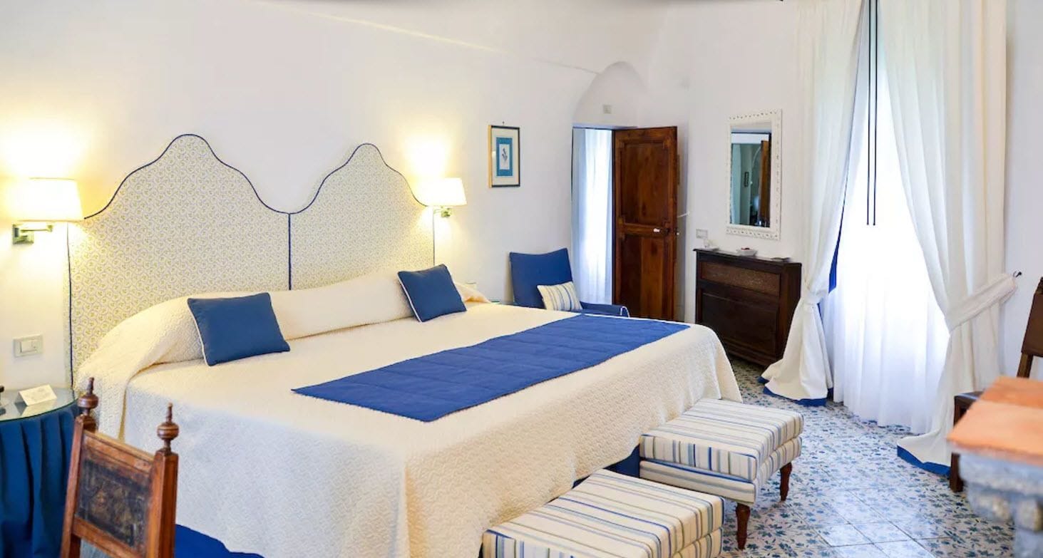 Un dormitorio ordenado con una cama grande, mesitas de noche, un espejo y una puerta.