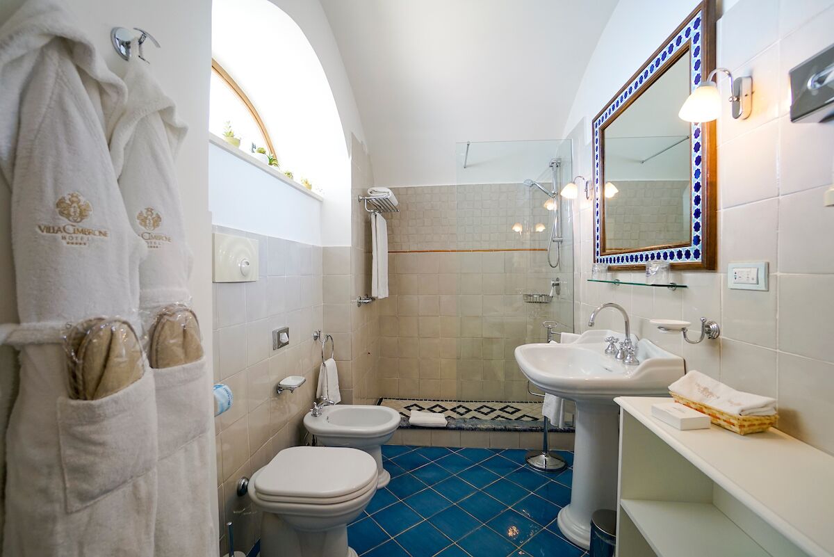 Une salle de bain équipée d’un bidet, d’un lavabo et d’un miroir. On peut voir des serviettes suspendues à un porte-serviettes et une zone douche.