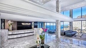 Eine großzügige Lobby mit Marmorboden, einer Rezeption und Sitzbereichen mit Blick auf den Ozean.