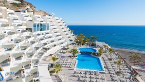 Ein Resort mit großem Pool, mehreren Balkonen und Blick auf den Strand.