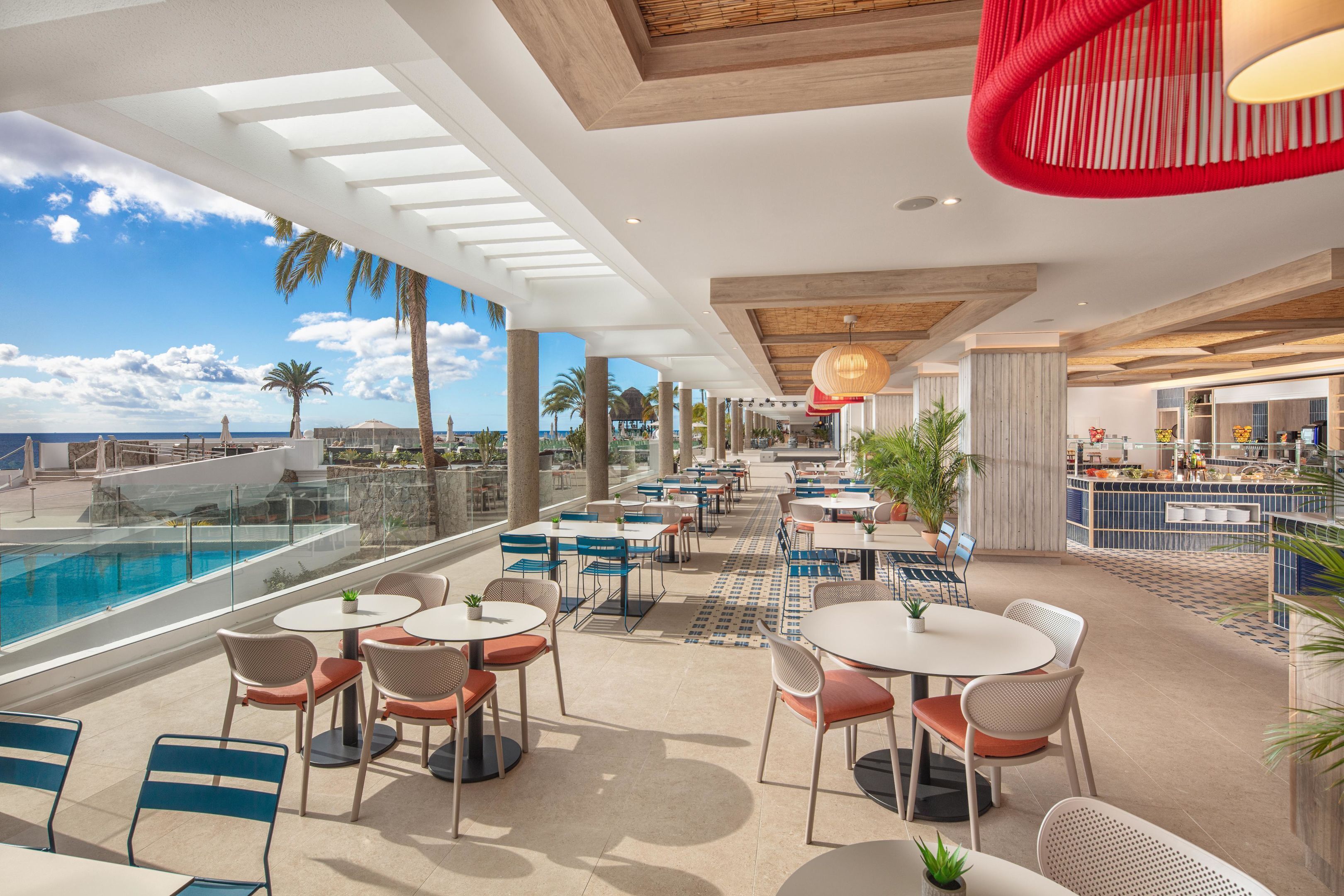 A rooftop bar with outdoor seating, a pool, and a view of the ocean.