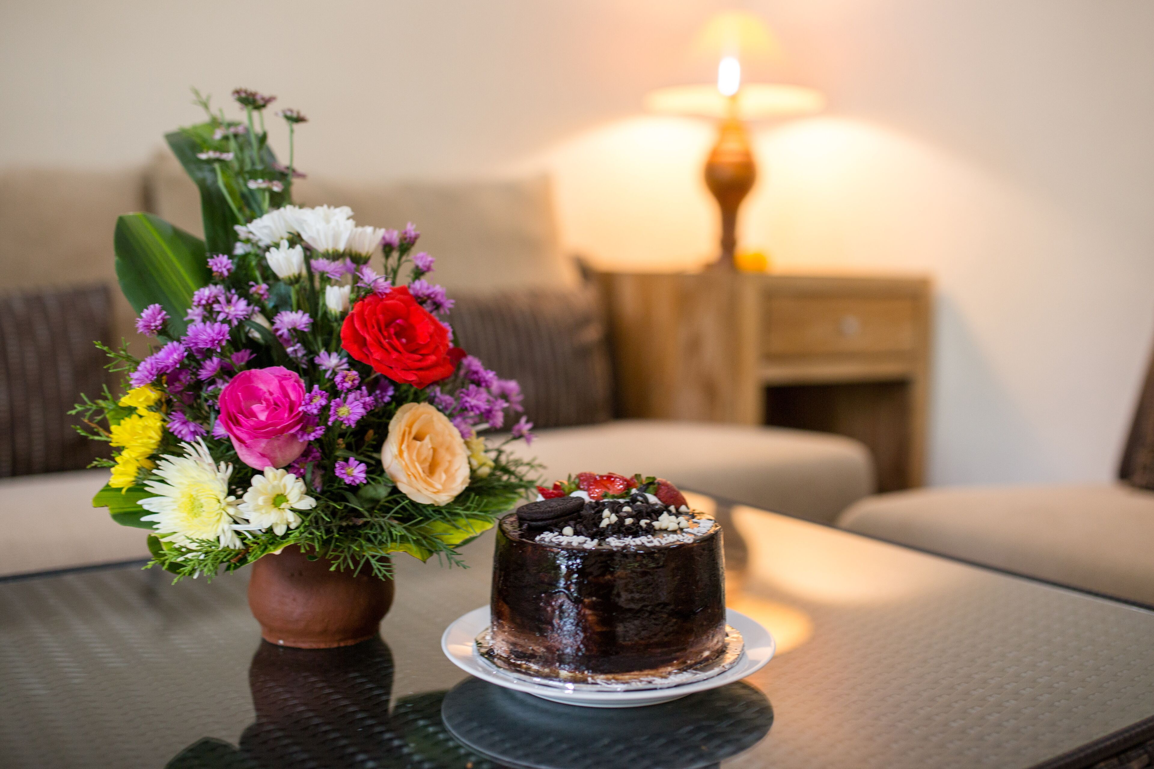 A table with a chocolate cake and a floral arrangement.