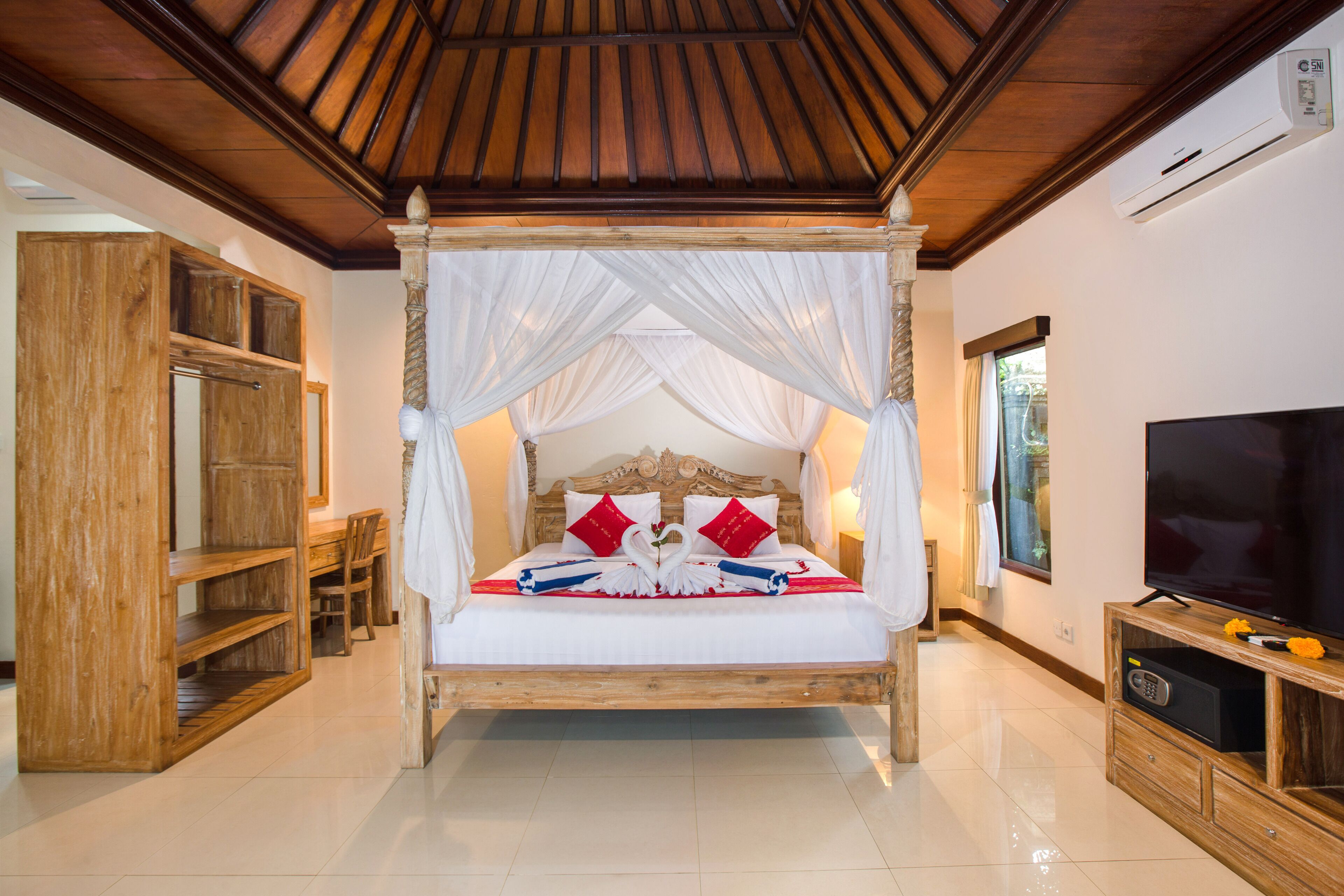 A four-poster bed with a canopy, a television, and a wooden cabinet.