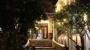A building with a staircase leading to the entrance, surrounded by trees and parked motorcycles. - Baan Busaba Hotel (Ko Pha-ngan)