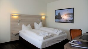A hotel room with a bed, a desk, and a wall-mounted picture. - Apartment-Vermietung Brunner (Rostock)