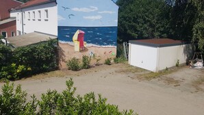 A building with a mural of a beach scene, including a chair and waves. - Apartment-Vermietung Brunner (Rostock)