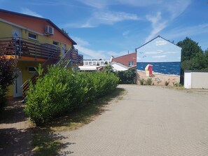 A paved pathway leading to a building with a red roof and a mural of a beach scene.