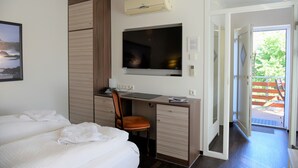 A hotel room with a bed, a desk with a chair, a TV, and an air conditioning unit. - Apartment-Vermietung Brunner (Rostock)