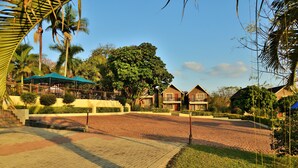 Un resort con un patio empedrado, palmeras y una zona de estar al aire libre techada.