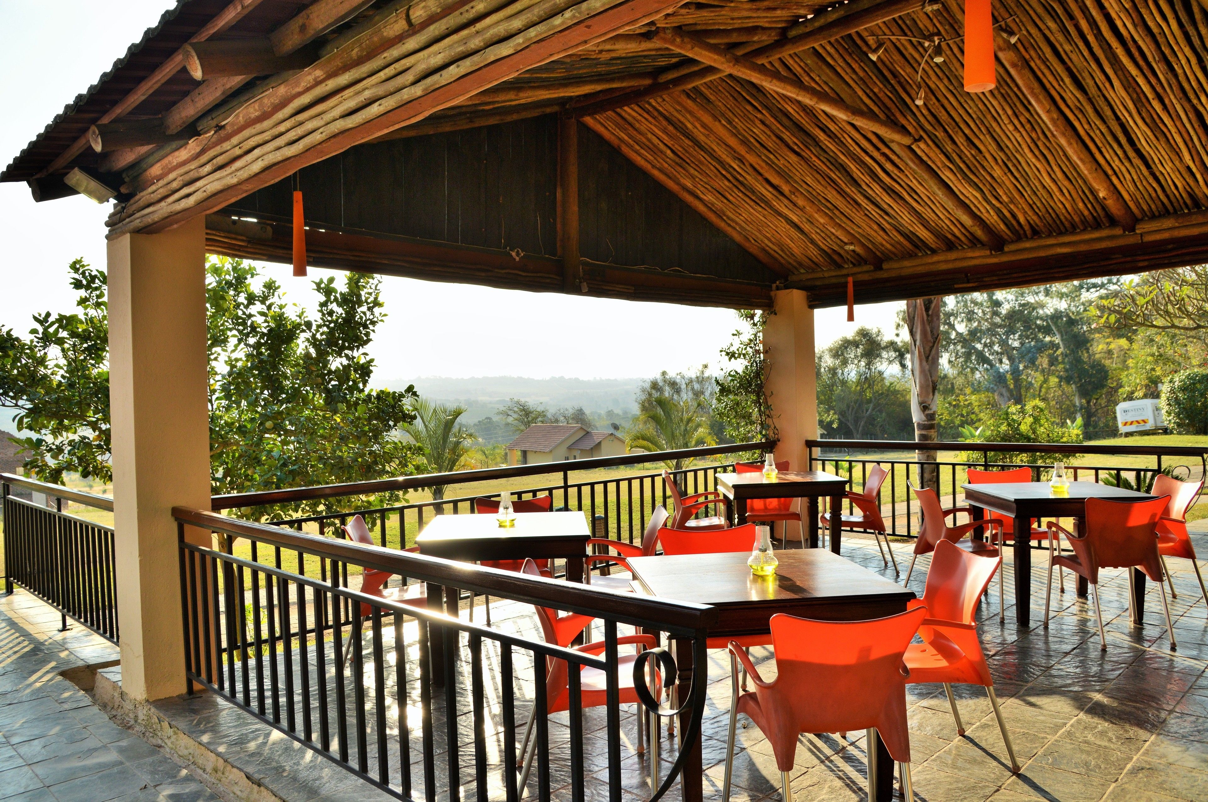 Une terrasse extérieure avec des tables et des chaises, un toit en bois et une vue sur le paysage.