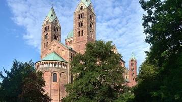 A historic building with two prominent towers and a central dome, surrounded by lush greenery.