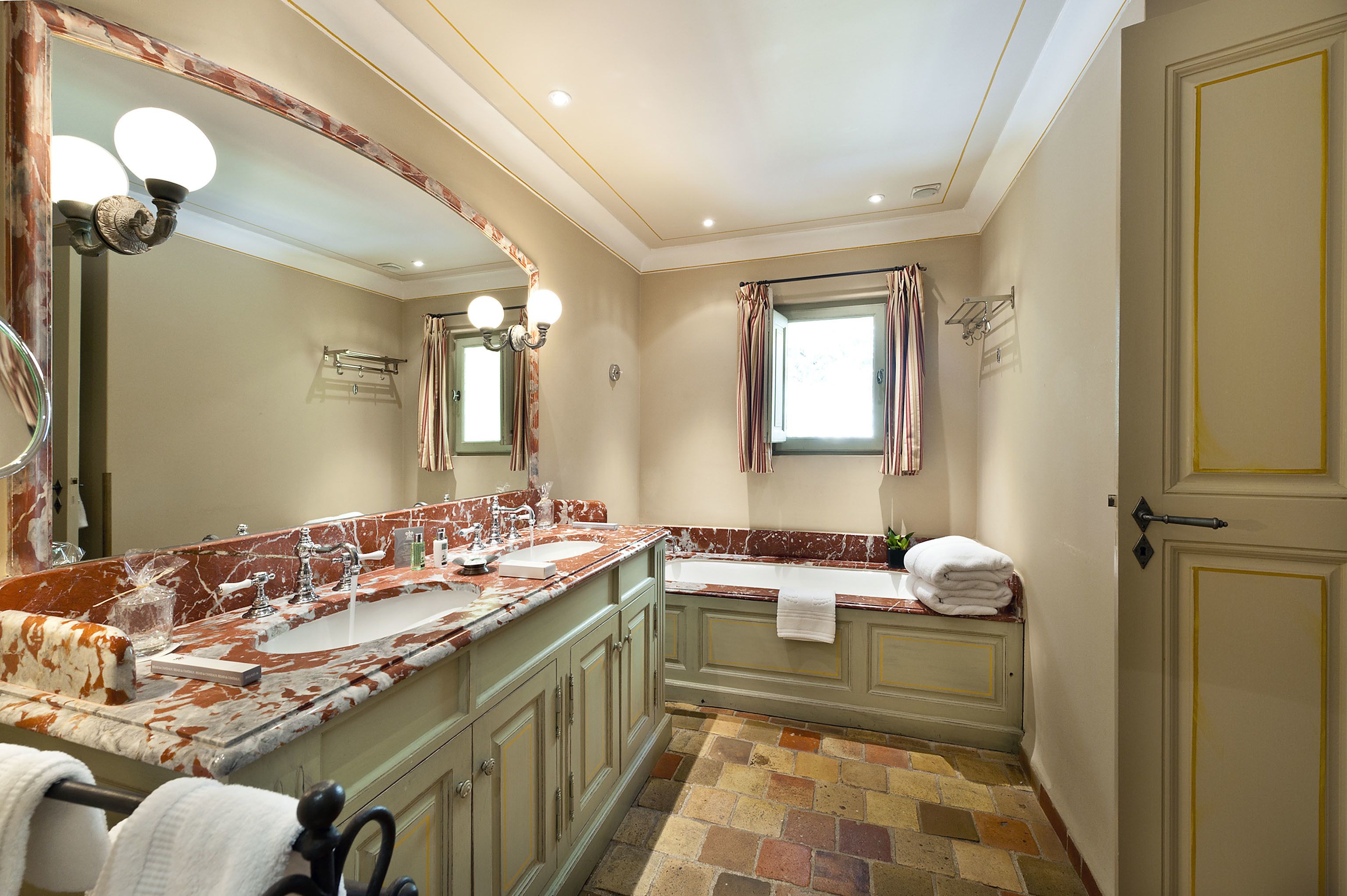 Un baño con dos lavamanos, una bañera, un espejo grande y un perchero para toallas.