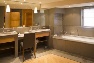 A modern bathroom with two sinks, a bathtub, and a large mirror.