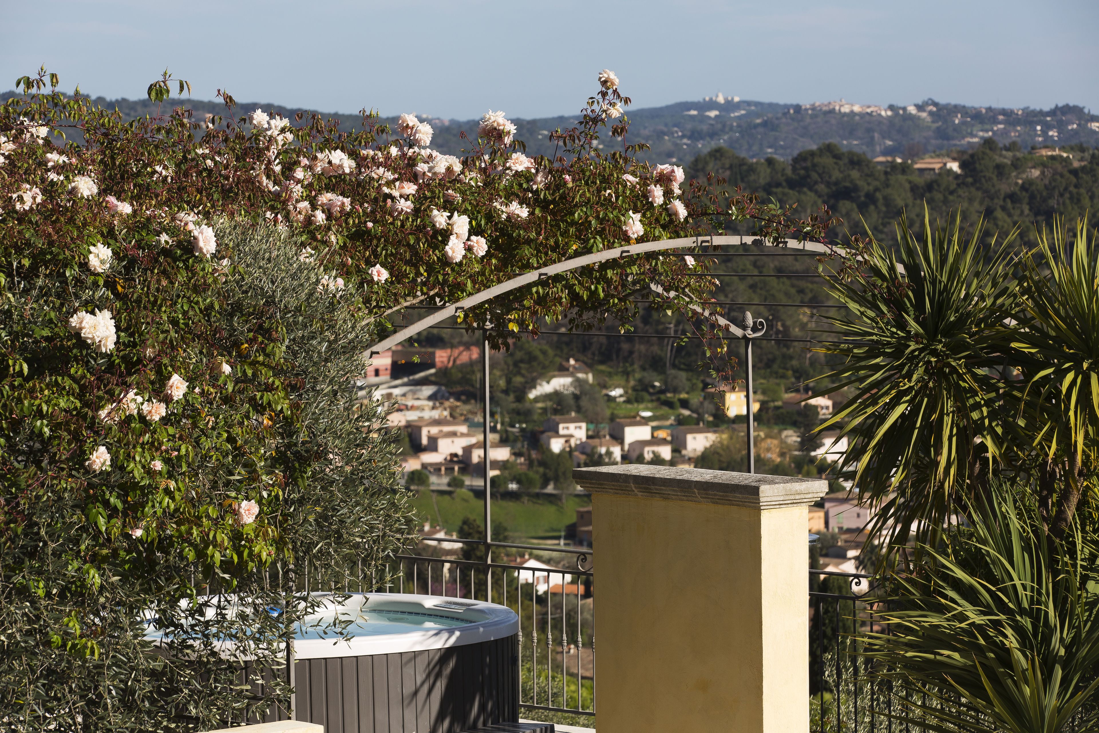 Un jacuzzi sur un balcon offrant une vue sur un quartier résidentiel et des collines en arrière-plan.