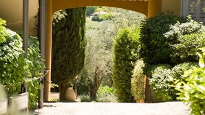 Un arco que da acceso a un jardín con setos bien cuidados y un farol.