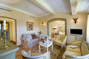 A living room with a sofa, armchairs, a coffee table, and a TV.