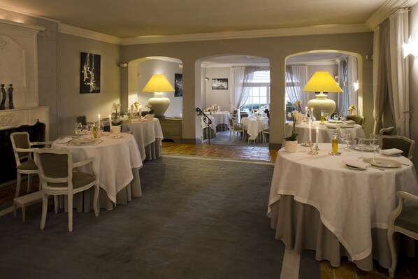 A dining area with multiple round tables set for guests, each with white tablecloths and candles. - La Bastide Saint Antoine (Grasse)